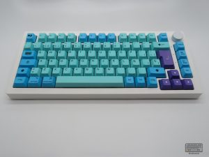 Set de keycaps LUCY de kbdmania en teclado 75%, PBT deep dye sub, compatible con Mac y PC, ISO Español y ANSI, colores celestes y gamas lilas.