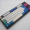 Teclas PBT redondeadas y uniformes de colores blancos y multicolor sobre un teclado negro ISO-TKL